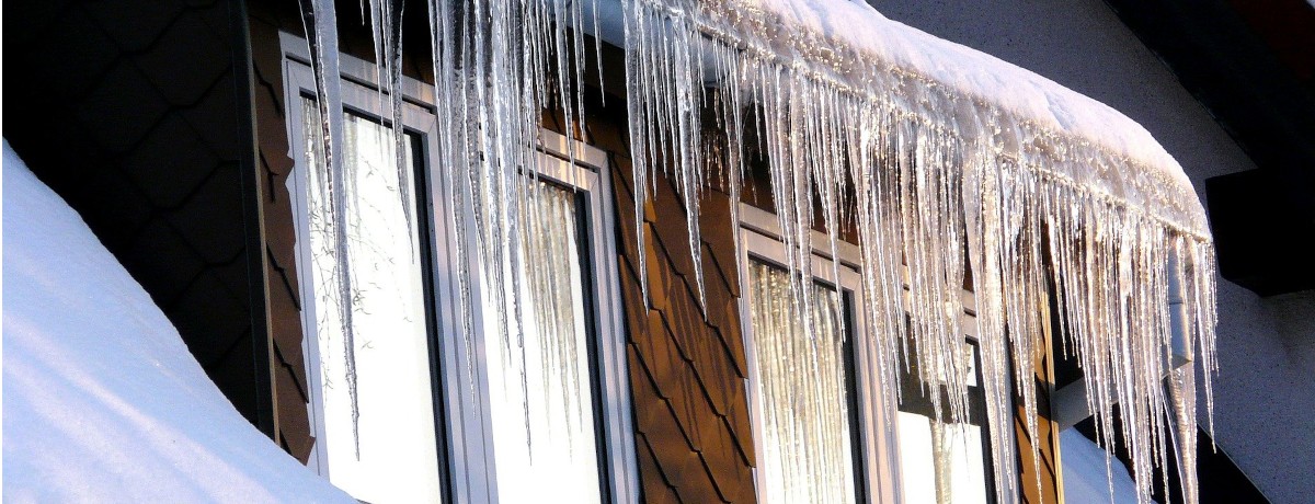 Long icicles hanging from the roof above a window on a Montreal house during winter – De longues stalactites de glace pendent du toit au-dessus d’une fenêtre d’une maison à Montréal en hiver.