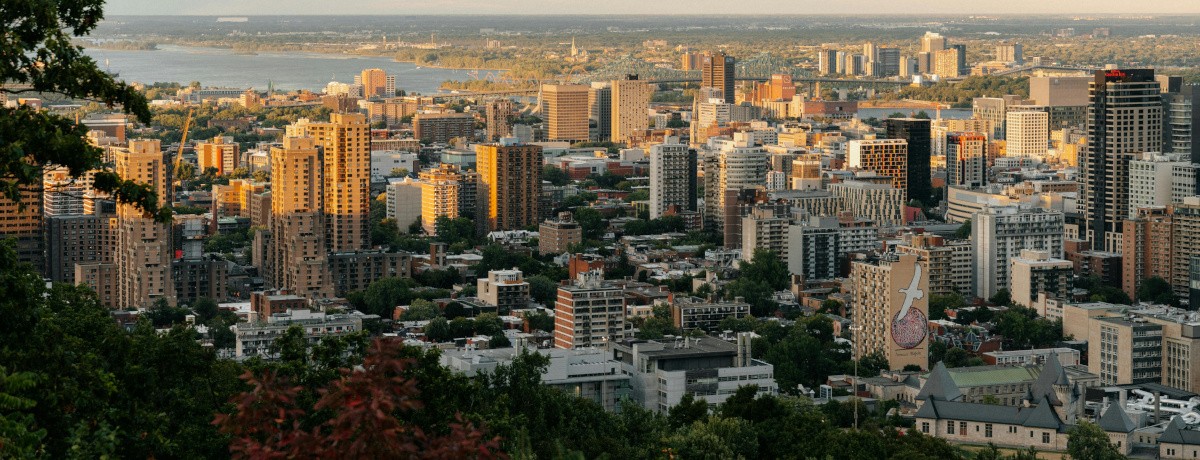 Panoramic view of Montreal skyline at sunset featuring downtown buildings, the St. Lawrence River, and surrounding neighborhoods - Vue panoramique du centre-ville de Montréal au coucher du soleil avec les immeubles, le fleuve Saint-Laurent et les quartiers environnants