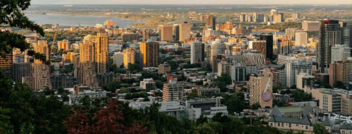 Panoramic view of Montreal skyline at sunset featuring downtown buildings, the St. Lawrence River, and surrounding neighborhoods - Vue panoramique du centre-ville de Montréal au coucher du soleil avec les immeubles, le fleuve Saint-Laurent et les quartiers environnants