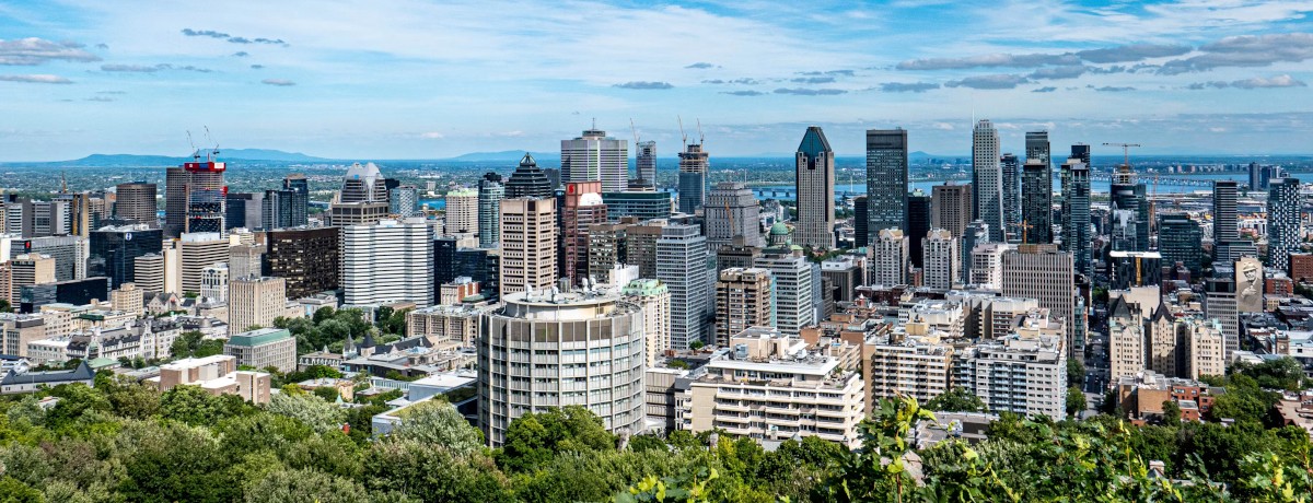 Summer skyline of downtown Montreal highlighting residential neighbourhoods and the city's evolving real estate market in June 2026. Vue estivale du centre-ville de Montréal mettant en valeur les quartiers résidentiels et l'évolution du marché immobilier en juin 2026.