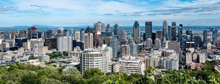 Summer skyline of downtown Montreal highlighting residential neighbourhoods and the city's evolving real estate market in June 2026. Vue estivale du centre-ville de Montréal mettant en valeur les quartiers résidentiels et l'évolution du marché immobilier en juin 2026.